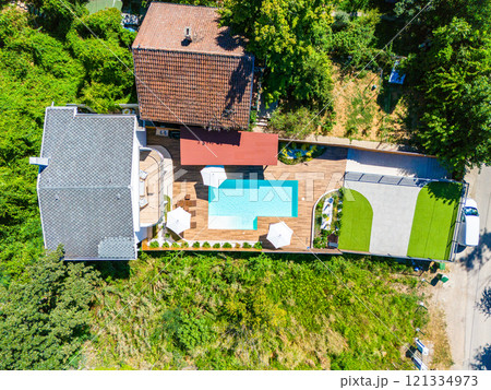 Aerial view of a modern backyard with a swimming pool, green lawn, and cozy patio Aerial view of a modern backyard with a swimming pool, green lawn, and cozy patio 121334973