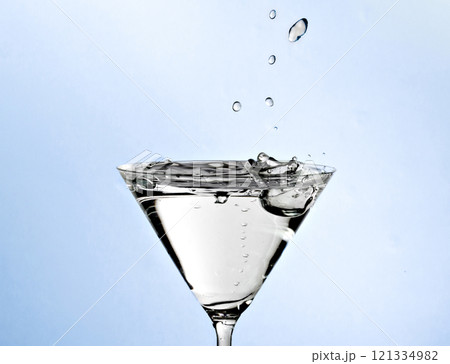 Close-up of water drop falling into a glass on white background	 121334982