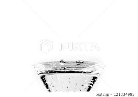 Close-up of water drop falling into a glass on white background	 121334983