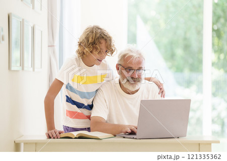 Senior man working on computer with grandchild Senior man working on computer with grandchild 121335362