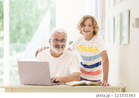 Senior man working on computer with grandchild 121335363