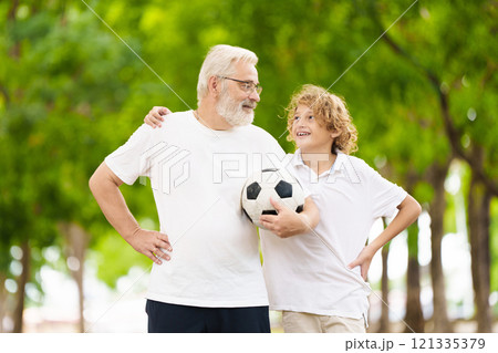 Grandfather and kids play football in summer park 121335379