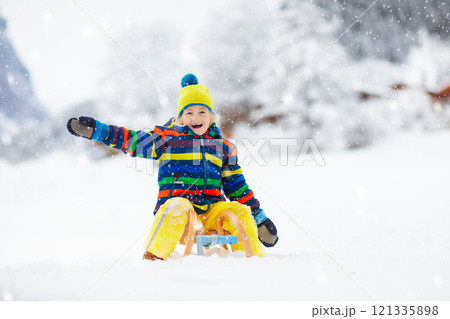 Boy on sled ride. Child sledding. Kid on sledge 121335898