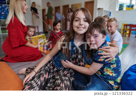 A girl and a boy with Down's syndrome in each other's arms spend time together in a preschool institution 121336322