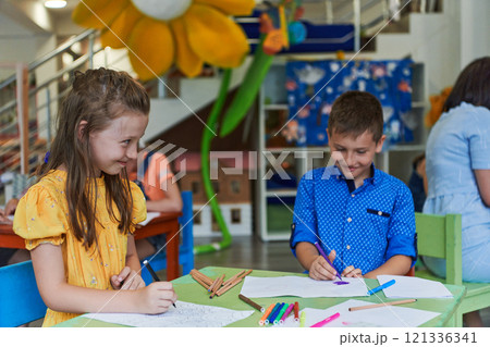 Cute girl and boy sit and draw together in preschool institution Cute girl and boy sit and draw together in preschool institution 121336341