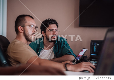 Programmers engrossed in deep collaboration, diligently working together to solve complex problems and develop innovative mobile applications with seamless functionality. 121336635