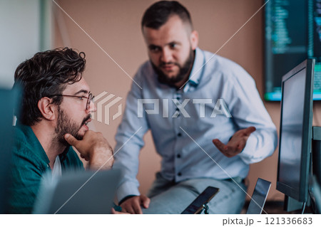 Programmers engrossed in deep collaboration, diligently working together to solve complex problems and develop innovative mobile applications with seamless functionality. 121336683