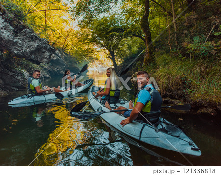 A group of friends enjoying having fun and kayaking while exploring the calm river, surrounding forest and large natural river canyons A group of friends enjoying having fun and kayaking while exploring the calm river, surrounding forest and large natural river canyons 121336818