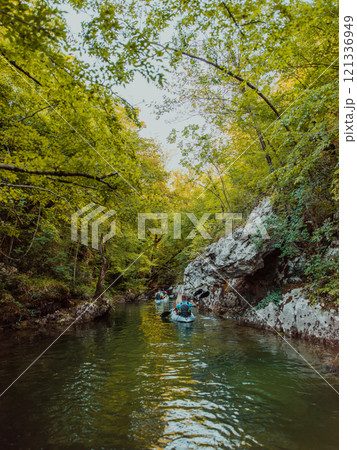 A group of friends enjoying having fun and kayaking while exploring the calm river, surrounding forest and large natural river canyons 121336949