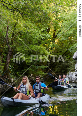 A group of friends enjoying having fun and kayaking while exploring the calm river, surrounding forest and large natural river canyons A group of friends enjoying having fun and kayaking while exploring the calm river, surrounding forest and large natural river canyons 121336995
