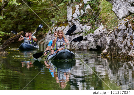 A group of friends enjoying having fun and kayaking while exploring the calm river, surrounding forest and large natural river canyons A group of friends enjoying having fun and kayaking while exploring the calm river, surrounding forest and large natural river canyons 121337024
