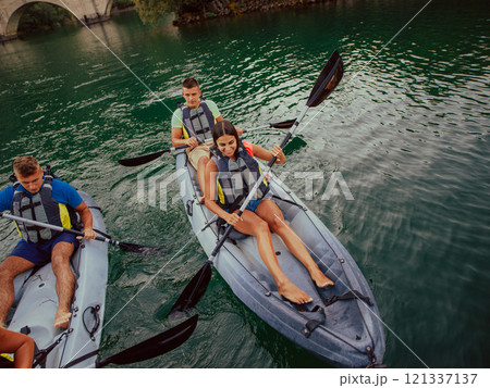A group of friends enjoying having fun and kayaking while exploring the calm river, surrounding forest and large natural river canyons 121337137