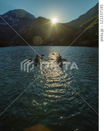 A group of friends enjoying fun and kayaking exploring the calm river, surrounding forest and large natural river canyons during an idyllic sunset. 121337195