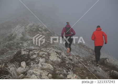 trail running couple man and woman running on a mountain path 121337243