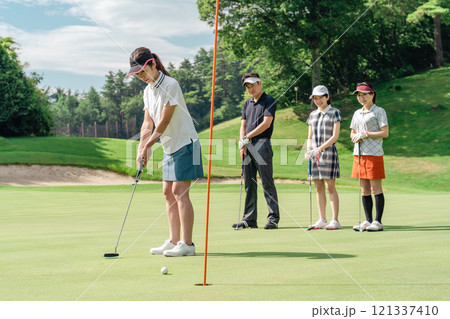 ゴルフ場のグリーンでゴルフをするゴルファーの女性(パター) 121337410