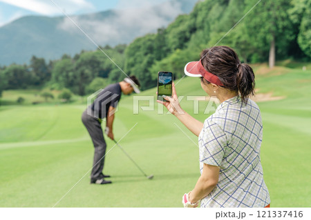 ゴルフ場でスマホを使って動画を撮ってスイングの確認をするゴルファー ゴルフ場でスマホを使って動画を撮ってスイングの確認をするゴルファー 121337416