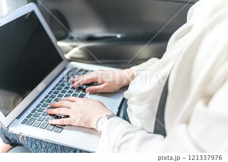 自動車の後部座席でノートパソコンで仕事をするビジネスウーマン（Web会議・オンライン会議・出張） 121337976