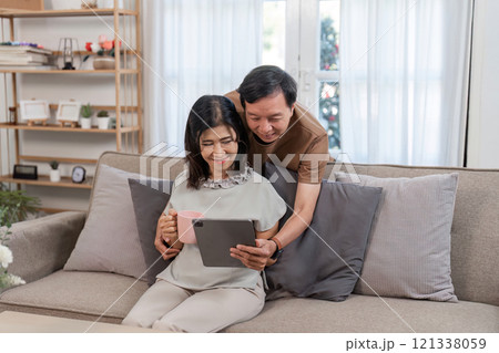 Retired Couple Enjoying Relaxation and Comfort in Their Cozy Living Room with Modern Decor and Warm Atmosphere Retired Couple Enjoying Relaxation and Comfort in Their Cozy Living Room with Modern Decor and Warm Atmosphere 121338059
