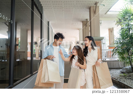 Joyful Family Shopping Experience Parents and Child Enjoying a Day Out with Shopping Bags in a Modern Mall Setting 121338067