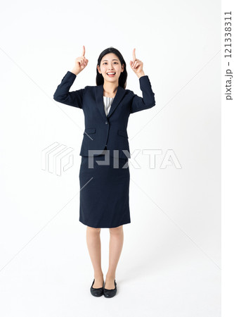 真上を指差すスーツを着た若い女性の全身ポートレート 真上を指差すスーツを着た若い女性の全身ポートレート 121338311