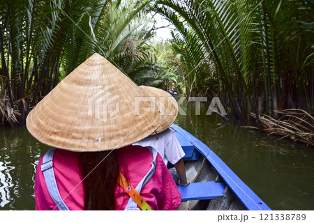 A woman wearing a straw hat is sitting in a boat with a man 121338789