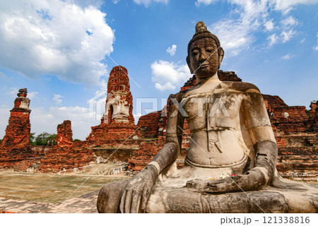 A statue of a Buddha is sitting in front of a large building 121338816
