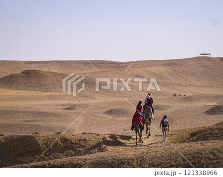 A group of people riding camels in a desert A group of people riding camels in a desert 121338966