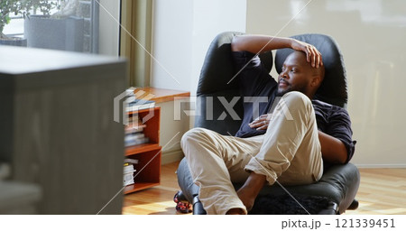 Front view of African american man relaxing on chair in a comfortable home 121339451