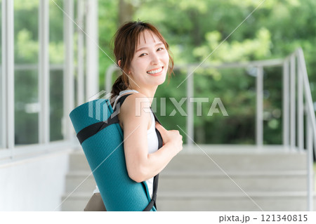 ヨガマットを持った健康的な女性（ヨガ講師・ヨギーニ） 121340815