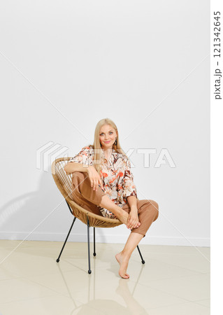 Casual look book featuring a model sitting comfortably in a chair against a minimalistic backdrop Casual look book featuring a model sitting comfortably in a chair against a minimalistic backdrop 121342645