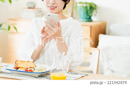 食事中にスマホを操作する若い女性 121342874