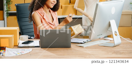 Young business owner woman prepare parcel box and standing check online orders for deliver 121343634