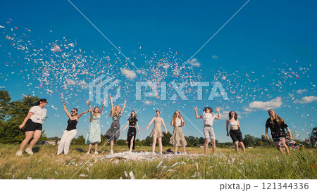 High school graduates joyfully tossing colorful confetti in a sunny field to celebrate their achievement 121344336