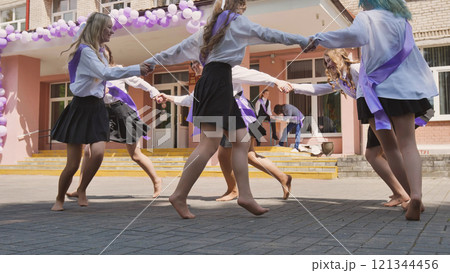 Female graduates dancing barefoot in the schoolyard on their last school day, celebrating the end of their studies Female graduates dancing barefoot in the schoolyard on their last school day, celebrating the end of their studies 121344456