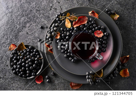 Black chokeberry drink and fresh berries on a black stone table. 121344705