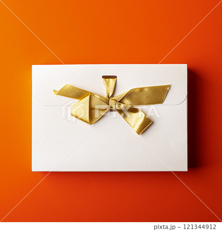 White gift box with gold ribbon isolated on orange background White gift box with gold ribbon isolated on orange background 121344912
