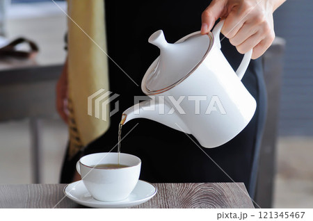 pouring tea , tea cup and tea pot or hot tea pouring tea , tea cup and tea pot or hot tea 121345467