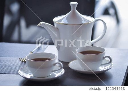 pouring tea , tea cup and tea pot or hot tea pouring tea , tea cup and tea pot or hot tea 121345468