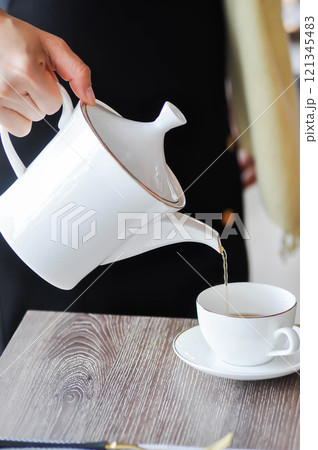pouring tea , tea cup and tea pot or hot tea pouring tea , tea cup and tea pot or hot tea 121345483