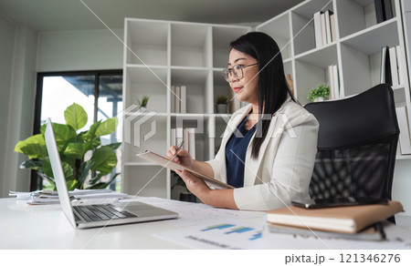 Middle-aged Business Woman Doing Paperwork and Working on Computer in Modern Office Setting Middle-aged Business Woman Doing Paperwork and Working on Computer in Modern Office Setting 121346276