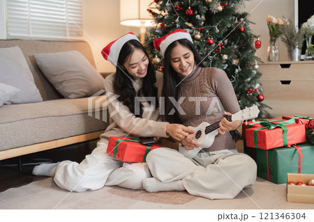 Joyful Young Couple Celebrating Christmas with Gifts and Music by the Tree in a Cozy Living Room Setting Joyful Young Couple Celebrating Christmas with Gifts and Music by the Tree in a Cozy Living Room Setting 121346304