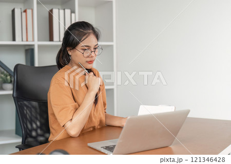 Young Woman Studying Online at Home with Laptop, Concentrating on Learning in a Modern Workspace Young Woman Studying Online at Home with Laptop, Concentrating on Learning in a Modern Workspace 121346428