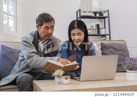 Elderly Couple Relaxing in Modern Living Room, Reading Book and Using Laptop, Cozy Home Environment, Senior Lifestyle, Comfortable and Peaceful Moments, Togetherness and Leisure Time 121346429
