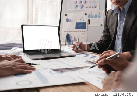 Business team working together on project with charts and laptop with white screen in modern office 121346506