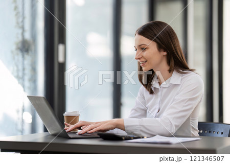 Professional Business Woman Working on a Desk with Laptop in Modern Office Environment 121346507