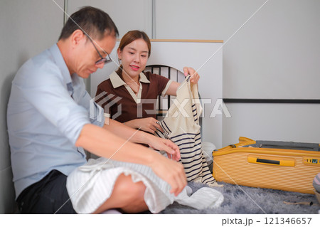 Father and Daughter Folding Clothes Together and Packing Them into a Suitcase for a Family Trip Father and Daughter Folding Clothes Together and Packing Them into a Suitcase for a Family Trip 121346657