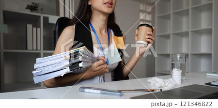 Focused Businesswoman Multitasking at Office Desk with Documents and Coffee in a Modern Workspace Environment 121346822
