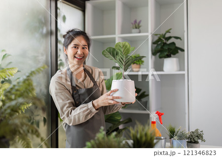 Woman Enjoying Indoor Gardening with Houseplants in a Modern Home Setting, Surrounded by Lush Greenery and Natural Light 121346823