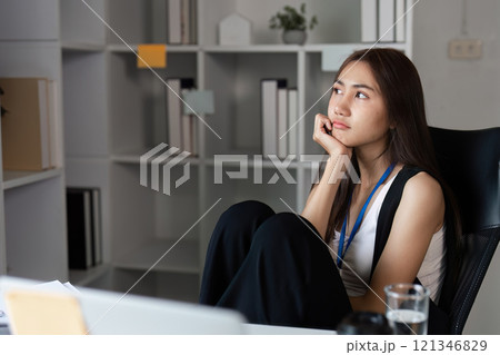 Bored Businesswoman Sitting at Desk in Modern Office, Daydreaming and Looking Away from Computer Screen 121346829