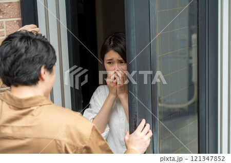 玄関先で訪問者に怯える女性 玄関先で訪問者に怯える女性 121347852